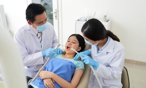 Young nurse assisting dentist when treating patient